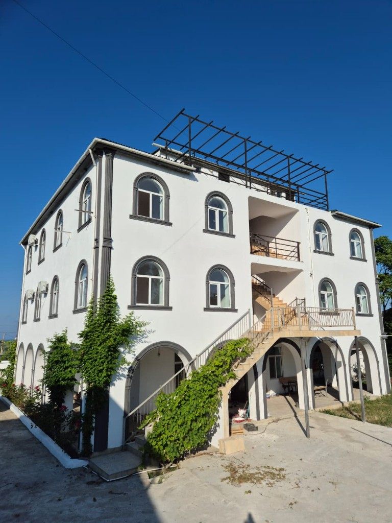Nabran Garden-in ağ fasadı, tağlı pəncərələr və yaşıl sarmaşıq